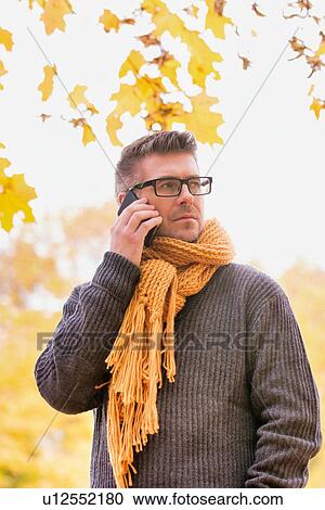 Portrait of mature attractive man talking on smartphone under maple tree in park View Large Photo Image Stock Image - Portrait of mature attractive man talking on smartphone under maple tree in park. Fotosearch