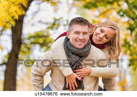 Portrait of mature attractive man giving his wife a piggy ride back in park View Large Photo Image Stock Photograph - Portrait of mature attractive man giving his wife a piggy ride back in park. Fotosearch