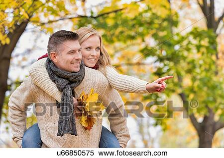 Portrait of mature attractive man giving his wife a piggy ride back in park View Large Photo Image Stock Photography - Portrait of mature attractive man giving his wife a piggy ride back in park. Fotosearch