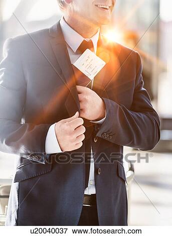 Stock Photo - Portrait of mature attractive businessman taking out his passport from his suit in airport. Fotosearch