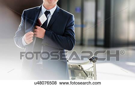 Stock Photo - Portrait of mature attractive businessman taking out his passport from his suit in airport. Fotosearch