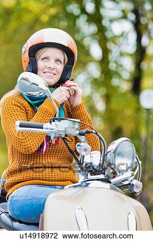 Portrait of mature beautiful woman putting her helmet on to ride motorbike in park View Large Photo Image Stock Image - Portrait of mature beautiful woman putting her helmet on to ride motorbike in park. Fotosearch