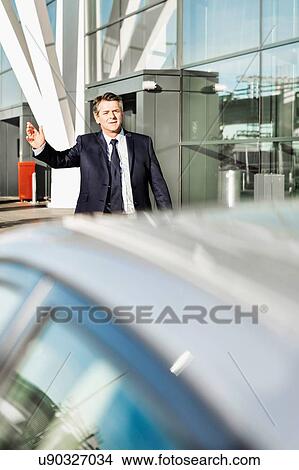 Portrait of mature businessman calling taxi in the airport View Large Photo Image Picture - Portrait of mature businessman calling taxi in the airport. Fotosearch