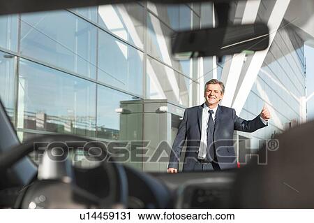 Stock Image - Portrait of mature businessman calling taxi in the airport. Fotosearch
