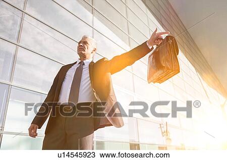 Portrait of mature businessman calling taxi in the airport View Large Photo Image Stock Image - Portrait of mature businessman calling taxi in the airport. Fotosearch