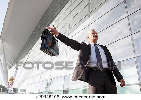 Portrait of mature businessman calling taxi in the airport View Large Photo Image Stock Photograph - Portrait of mature businessman calling taxi in the airport. Fotosearch