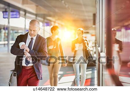 Portrait of mature businessman holding a cup of coffee while looking at his watch View Large Photo Image Stock Image - Portrait of mature businessman holding a cup of coffee while looking at his watch. Fotosearch