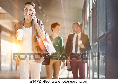 Stock Photograph - Portrait of mature businessman holding a cup of coffee while looking at his watch. Fotosearch