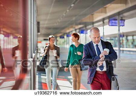 Portrait of mature businessman holding a cup of coffee while looking at his watch View Large Photo Image Stock Photograph - Portrait of mature businessman holding a cup of coffee while looking at his watch. Fotosearch