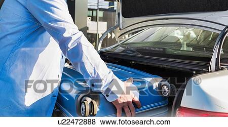 Portrait of mature businessman putting his luggage on car trunk with lens flare View Large Photo Image Stock Photo - Portrait of mature businessman putting his luggage on car trunk with lens flare . Fotosearch