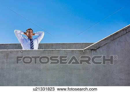 Stock Image - Portrait of mature businessman relaxing on rooftop . Fotosearch