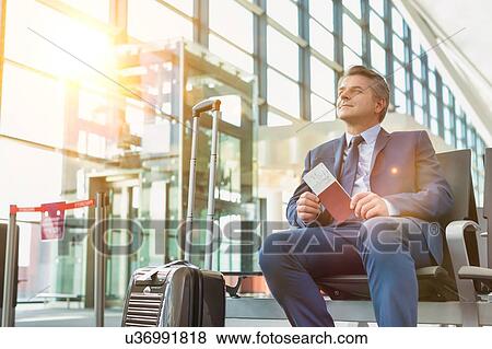 Portrait of Mature businessman sitting and holding his passport while waiting in gate for boarding at airport View Large Photo Image Stock Photo - Portrait of Mature businessman sitting and holding his passport while waiting in gate for boarding at airport. Fotosearch