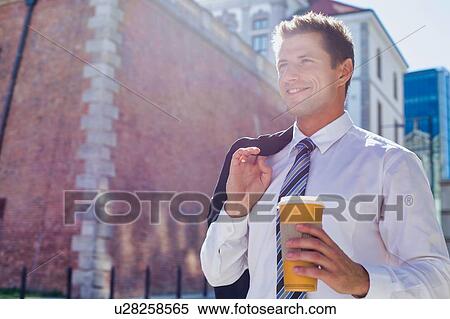 Stock Photography - Portrait of mature businessman walking while holding a cup of coffee. Fotosearch