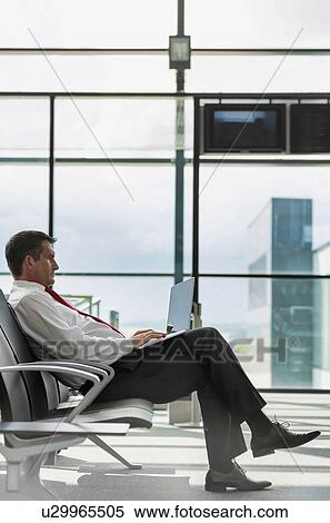 Stock Photography - Portrait of mature businessman working on his laptop while sitting and waiting for flight in airport. Fotosearch