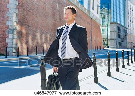 Stock Photo - Portrait of mature confident man walking on pavement. Fotosearch