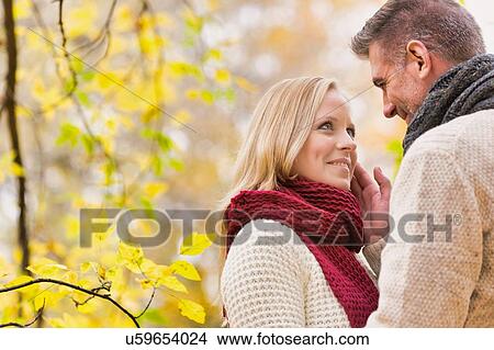 Picture - Portrait of Mature couple enjoying autumn while showing affection in park. Fotosearch