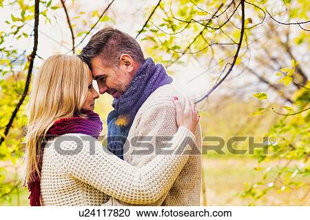 Portrait of Mature couple enjoying autumn while showing affection in park View Large Photo Image Stock Image - Portrait of Mature couple enjoying autumn while showing affection in park. Fotosearch