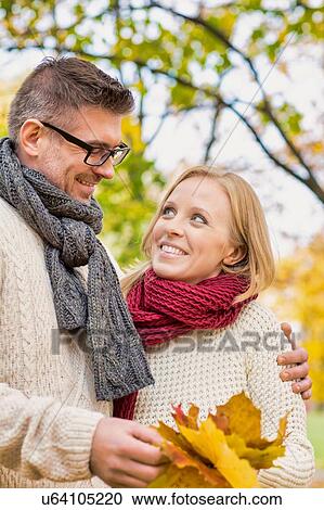 Portrait of mature couple holding maple leaves in park View Large Photo Image Stock Image - Portrait of mature couple holding maple leaves in park. Fotosearch