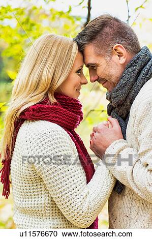 Stock Image - Portrait of mature couple making a vow in park. Fotosearch