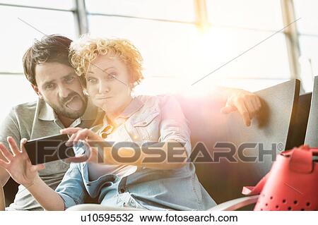 Portrait of mature couple taking selfie while waiting for boarding in airport View Large Photo Image Stock Image - Portrait of mature couple taking selfie while waiting for boarding in airport. Fotosearch