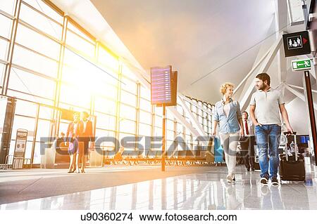 Portrait of mature couple walking while talking in airport View Large Photo Image Picture - Portrait of mature couple walking while talking in airport. Fotosearch