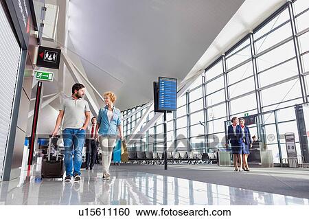 Portrait of mature couple walking while talking in airport View Large Photo Image Stock Image - Portrait of mature couple walking while talking in airport. Fotosearch