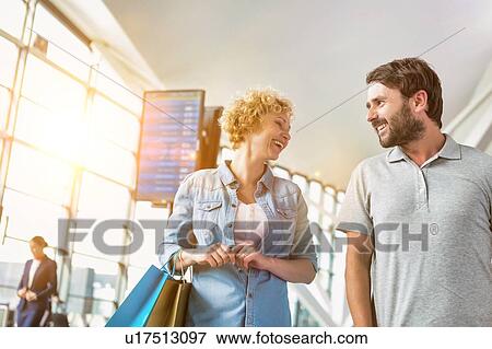 Stock Photo - Portrait of mature couple walking while talking in airport. Fotosearch