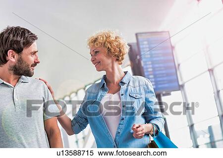 Portrait of mature couple walking while talking in airport View Large Photo Image Stock Photography - Portrait of mature couple walking while talking in airport. Fotosearch