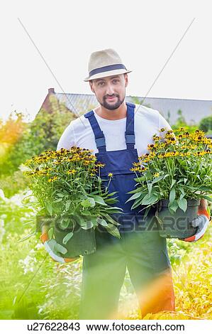 Portrait of mature gardener carrying flowers in shop View Large Photo Image Stock Image - Portrait of mature gardener carrying flowers in shop. Fotosearch