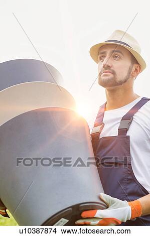 Picture - Portrait of mature male gardener carrying pots in shop. Fotosearch