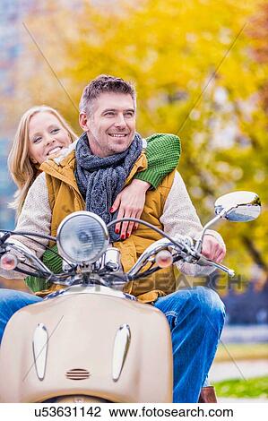 Portrait of mature man driving motorbike with his wife in park View Large Photo Image Stock Image - Portrait of mature man driving motorbike with his wife in park. Fotosearch