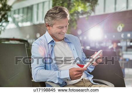 Portrait of mature man holding airplane toy in airport while waiting for boarding with lens flare View Large Photo Image Stock Photography - Portrait of mature man holding airplane toy in airport while waiting for boarding with lens flare. Fotosearch
