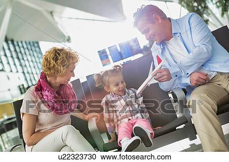 Stock Image - Portrait of mature man playing airplane with his cute daughter in airport while waiting for boarding. Fotosearch