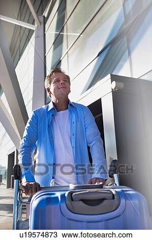 Portrait of mature man pushing cart with his suitcase in airport View Large Photo Image Stock Image - Portrait of mature man pushing cart with his suitcase in airport. Fotosearch