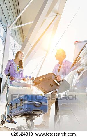 Portrait of mature man putting luggage on car trunk with lens flare View Large Photo Image Stock Photo - Portrait of mature man putting luggage on car trunk with lens flare. Fotosearch