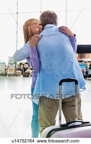 Picture - Portrait of mature man reuniting with his daughter in airport. Fotosearch