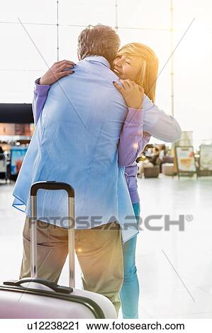 Stock Image - Portrait of mature man reuniting with his daughter in airport. Fotosearch