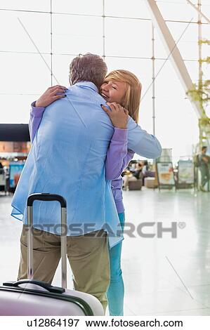 Stock Photo - Portrait of mature man reuniting with his daughter in airport. Fotosearch