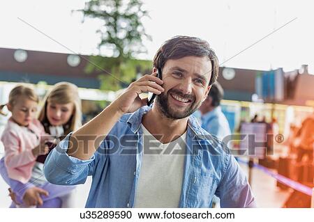 Portrait of mature man smiling while talking on smartphone in airport View Large Photo Image Stock Image - Portrait of mature man smiling while talking on smartphone in airport. Fotosearch