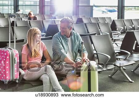 Portrait of mature man talking to her daughter while waiting and sitting in airport with yellow lens flare View Large Photo Image Stock Image - Portrait of mature man talking to her daughter while waiting and sitting in airport with yellow lens flare. Fotosearch
