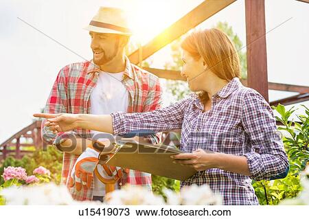 Portrait of mature owner writing report on clipboard with the gardener in shop View Large Photo Image Stock Image - Portrait of mature owner writing report on clipboard with the gardener in shop. Fotosearch