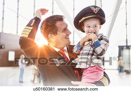 Portrait of mature pilot carrying cute little child in airport View Large Photo Image Stock Image - Portrait of mature pilot carrying cute little child in airport. Fotosearch