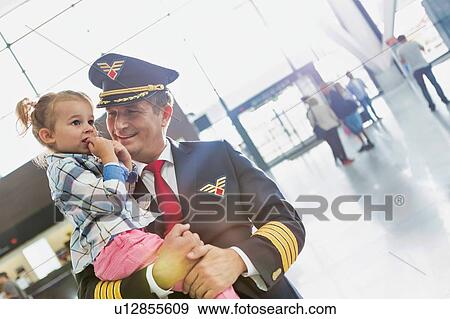 Portrait of mature pilot carrying cute little child in airport View Large Photo Image Stock Photo - Portrait of mature pilot carrying cute little child in airport. Fotosearch