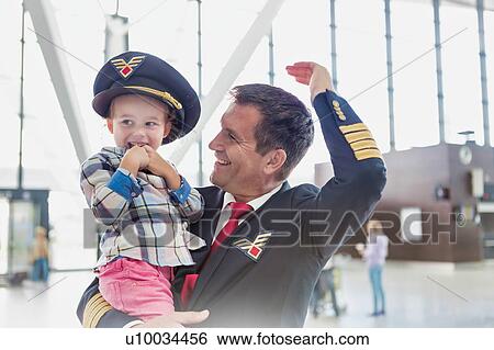 Portrait of mature pilot carrying cute little child in airport View Large Photo Image Stock Photograph - Portrait of mature pilot carrying cute little child in airport. Fotosearch
