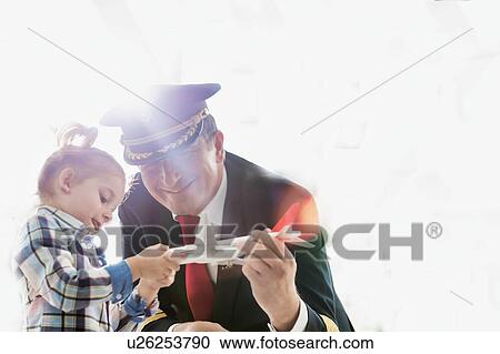 Stock Image - Portrait of mature pilot holding airplane toy while playing with cute little girl in airport. Fotosearch