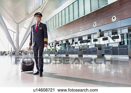 Stock Image - Portrait of mature pilot standing in check in area at airport . Fotosearch