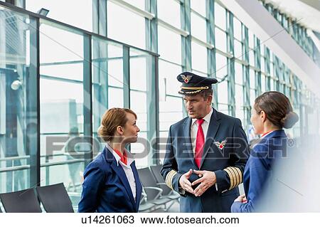 Portrait of Mature pilot talking to flight attendants in airport with yellow lens flare View Large Photo Image Stock Image - Portrait of Mature pilot talking to flight attendants in airport with yellow lens flare. Fotosearch