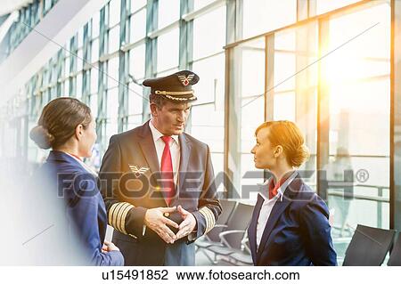 Portrait of Mature pilot talking to flight attendants in airport with yellow lens flare View Large Photo Image Stock Image - Portrait of Mature pilot talking to flight attendants in airport with yellow lens flare. Fotosearch