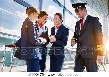 Portrait of mature pilot talking with young attractive flight attendants during arrival in airport View Large Photo Image Picture - Portrait of mature pilot talking with young attractive flight attendants during arrival in airport. Fotosearch