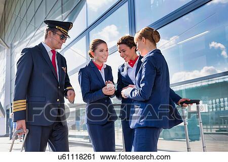 Portrait of mature pilot talking with young attractive flight attendants during arrival in airport View Large Photo Image Stock Image - Portrait of mature pilot talking with young attractive flight attendants during arrival in airport. Fotosearch